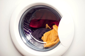 White washing machine door full of clothes, close up. Laundry concept