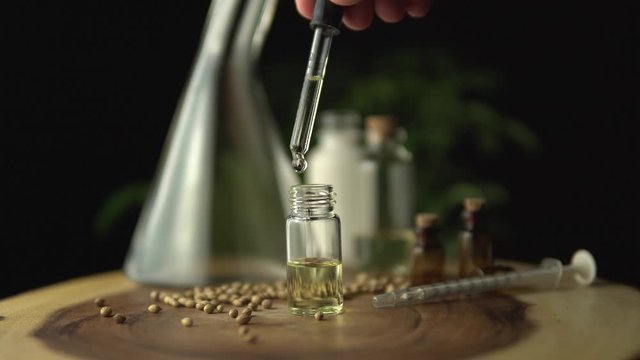 Pipette droplet dosing licensed cannabis CBD oil for medical purposes. Hydroponic biological and ecological hemp plant and herbal pharmaceutical clinic study concept.