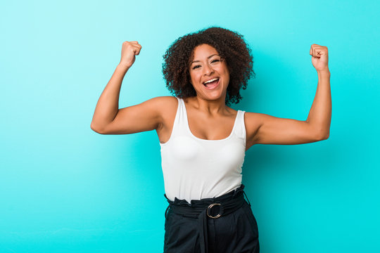 Young african american woman showing strength gesture with arms, symbol of feminine power