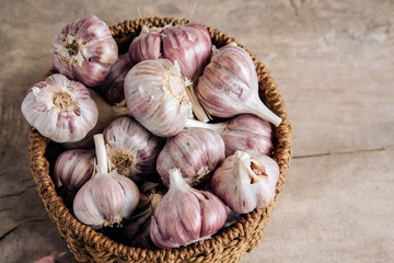 Garlic in a wicker basket on a wooden table background. Top view. Copy, empty space for text