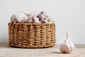Garlic in a wicker basket on a wooden table background. Copy, empty space for text