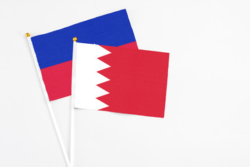 Bahrain and Haiti stick flags on white background. High quality fabric, miniature national flag. Peaceful global concept.White floor for copy space.