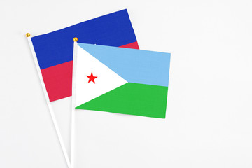 Djibouti and Haiti stick flags on white background. High quality fabric, miniature national flag. Peaceful global concept.White floor for copy space.
