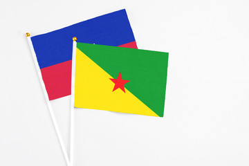 French Guiana and Haiti stick flags on white background. High quality fabric, miniature national flag. Peaceful global concept.White floor for copy space.