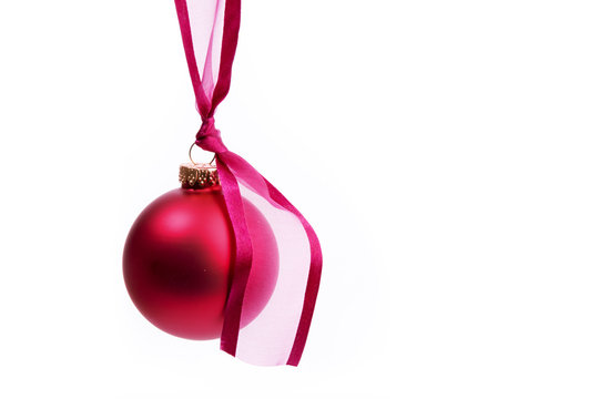 A Large Red Christmas Tree Ornament Hanging From A Pink Ribbon Isolated On White