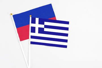 Greece and Haiti stick flags on white background. High quality fabric, miniature national flag. Peaceful global concept.White floor for copy space.