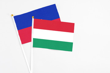Hungary and Haiti stick flags on white background. High quality fabric, miniature national flag. Peaceful global concept.White floor for copy space.