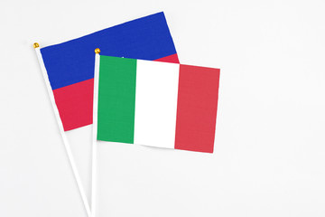 Italy and Haiti stick flags on white background. High quality fabric, miniature national flag. Peaceful global concept.White floor for copy space.