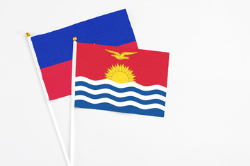 Kiribati and Haiti stick flags on white background. High quality fabric, miniature national flag. Peaceful global concept.White floor for copy space.