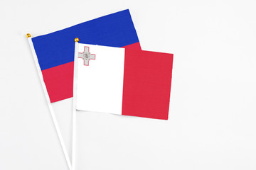 Malta and Haiti stick flags on white background. High quality fabric, miniature national flag. Peaceful global concept.White floor for copy space.