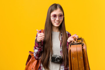 Young asian woman holding a suitcase smiling and raising thumb up