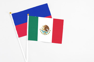 Mexico and Haiti stick flags on white background. High quality fabric, miniature national flag. Peaceful global concept.White floor for copy space.