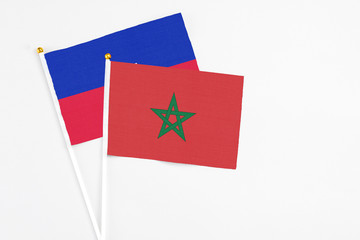 Morocco and Haiti stick flags on white background. High quality fabric, miniature national flag. Peaceful global concept.White floor for copy space.