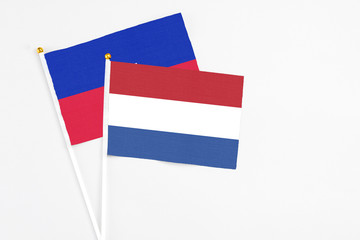 Netherlands and Haiti stick flags on white background. High quality fabric, miniature national...