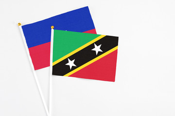 Saint Kitts And Nevis and Haiti stick flags on white background. High quality fabric, miniature national flag. Peaceful global concept.White floor for copy space.