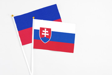 Slovakia and Haiti stick flags on white background. High quality fabric, miniature national flag. Peaceful global concept.White floor for copy space.