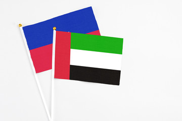 United Arab Emirates and Haiti stick flags on white background. High quality fabric, miniature national flag. Peaceful global concept.White floor for copy space.