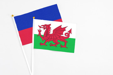 Wales and Haiti stick flags on white background. High quality fabric, miniature national flag. Peaceful global concept.White floor for copy space.
