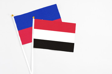 Yemen and Haiti stick flags on white background. High quality fabric, miniature national flag. Peaceful global concept.White floor for copy space.