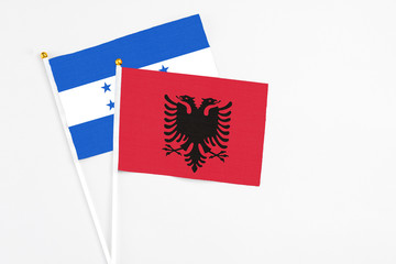 Albania and Honduras stick flags on white background. High quality fabric, miniature national flag. Peaceful global concept.White floor for copy space.