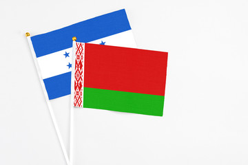 Belarus and Honduras stick flags on white background. High quality fabric, miniature national flag. Peaceful global concept.White floor for copy space.