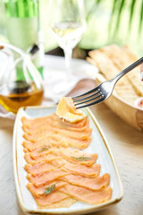 Closeup of salted and smoked salmon or trout fillet on a fork . Thin slices of red fish with lemon close up. Restaurant menu