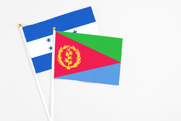 Eritrea and Honduras stick flags on white background. High quality fabric, miniature national flag. Peaceful global concept.White floor for copy space.