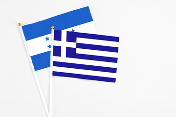 Obraz premium Greece and Honduras stick flags on white background. High quality fabric, miniature national flag. Peaceful global concept.White floor for copy space.