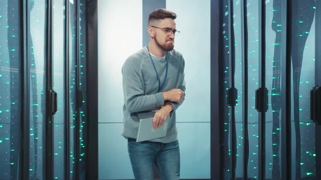Euphoric data center engineer with tablet dancing in high tech server room having fun time enjoying end of working day. Fun people at work.
