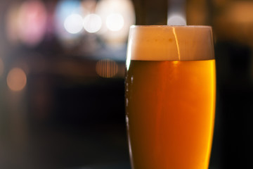full glass of beer on blurred lights background - obrazy, fototapety, plakaty