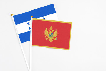 Montenegro and Honduras stick flags on white background. High quality fabric, miniature national flag. Peaceful global concept.White floor for copy space.