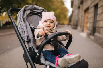 Cute little baby in pram. Adorable baby girl in autumn sitting in her pram