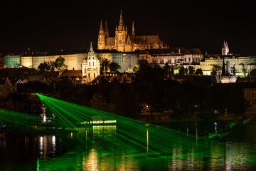 Prague castle with Vltava river in the foreground at the rays of the green laser, Prague.