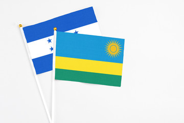 Rwanda and Honduras stick flags on white background. High quality fabric, miniature national flag. Peaceful global concept.White floor for copy space.