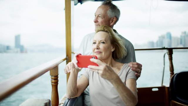 Caucasian couple taking smart phone pictures Victoria harbor 