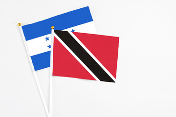 Trinidad And Tobago and Honduras stick flags on white background. High quality fabric, miniature national flag. Peaceful global concept.White floor for copy space.