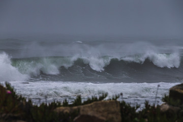Storm at sea, storm warning on the coast. Thunderclouds and big sea waves during a storm. Restless sea during the rain.