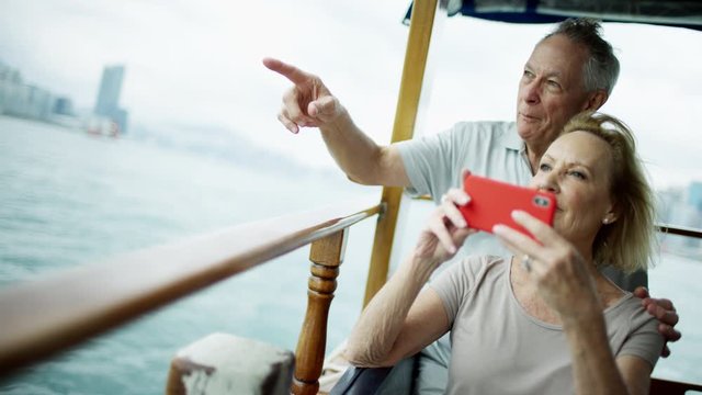 Senior couple taking travel photos on mobile phone