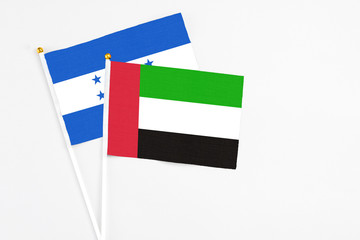 United Arab Emirates and Honduras stick flags on white background. High quality fabric, miniature national flag. Peaceful global concept.White floor for copy space.