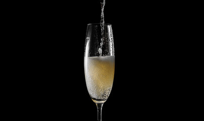 pour champagne into an empty glass. on a black background © Mykhailovskyi
