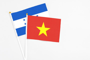 Vietnam and Honduras stick flags on white background. High quality fabric, miniature national flag. Peaceful global concept.White floor for copy space.