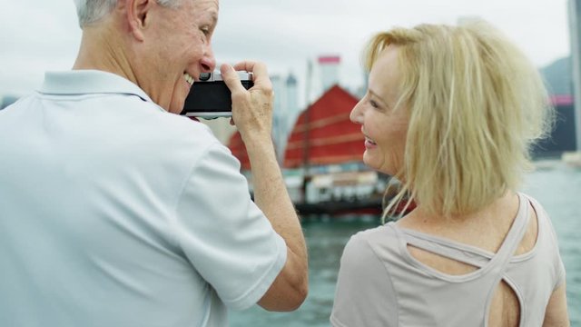 Caucasian couple taking photographic pictures red sail junk