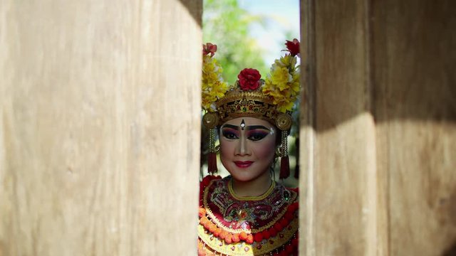 Portrait view dancing Balinese females opening temple doors 