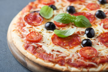 Pizza with chorizo, mozzarella cheese, cherry tomatoes, black olives and oregano. Home made food. Concept for a tasty and hearty meal. Close up.  
