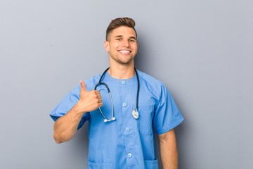 Young nurse man smiling and raising thumb up