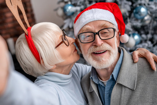Happy smiling senior couple in hats taking selfie at home