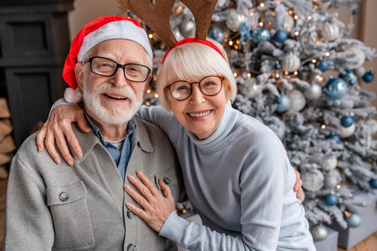 Portrait of happy smiling senior couple in santa hats celebrating at home