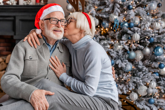 Senior couple celebrating christmas at home and elderly woman kissing his husband