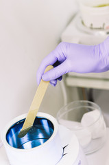 hand holding hot wax in white bowl