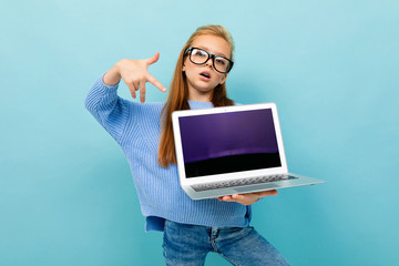 portrait of a dancing girl with a laptop on a background of blue wall